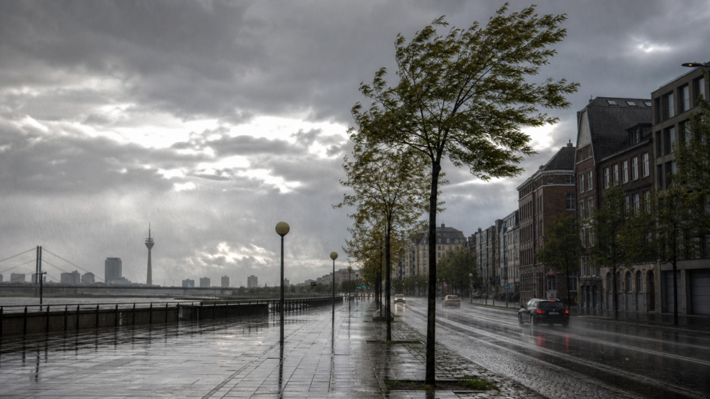 Dunkle Wolken und Regen in einer Stadt als Symbolbild für die aktuelle Wetterlage in Nordrhein-Westfalen.