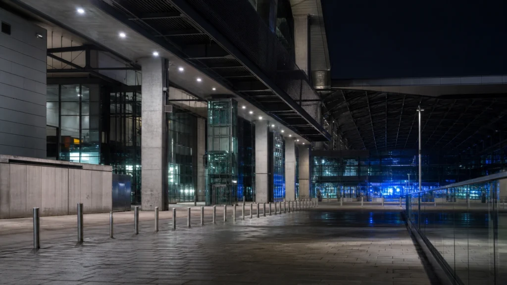 KI-generiertes Symbolbild eines menschenleeren modernen Bahnhofsbereichs bei Nacht.